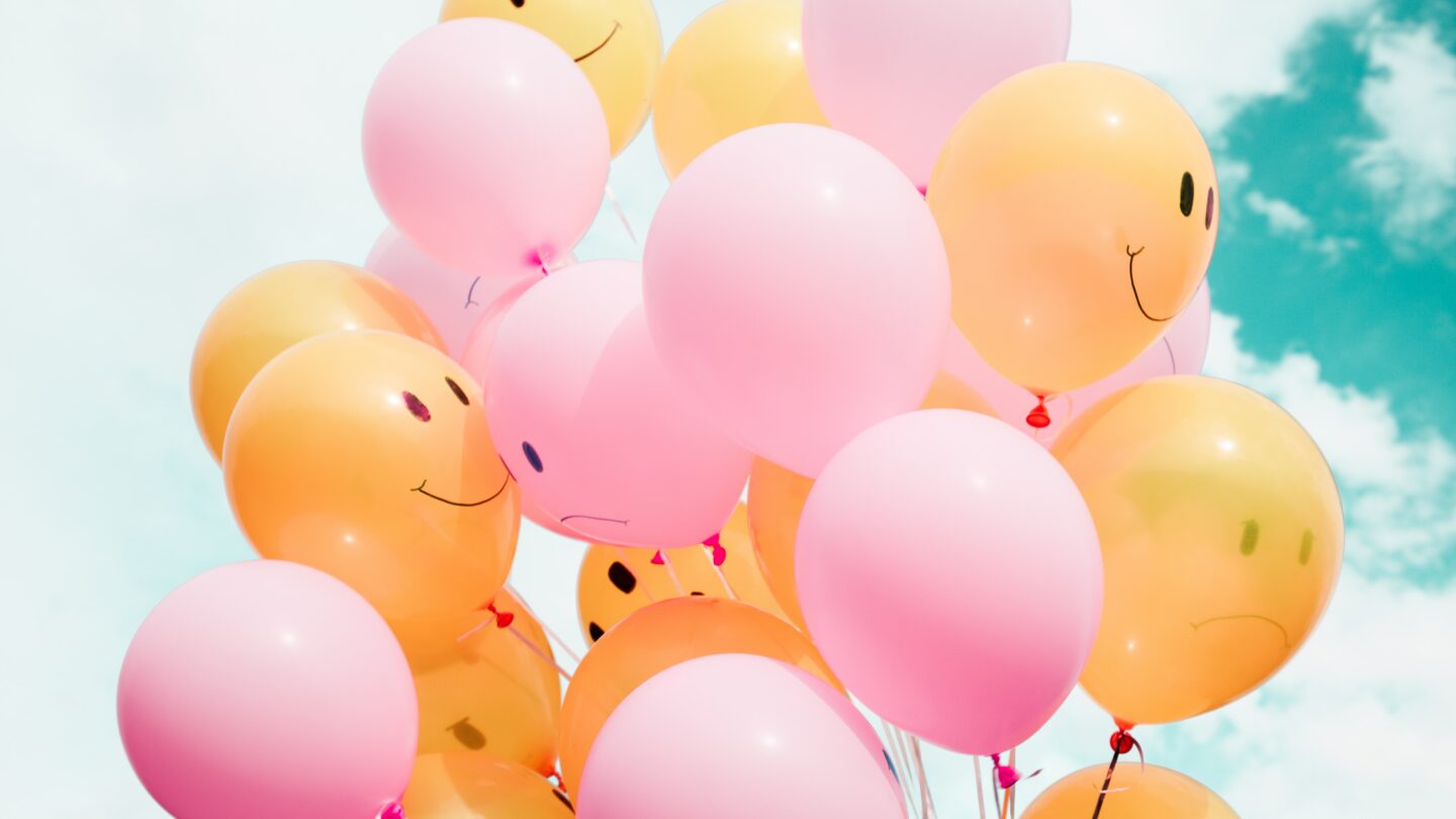 pink and orange balloons with happy and sad faces